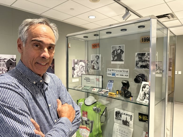 A man standing next to a photography display in a museum.